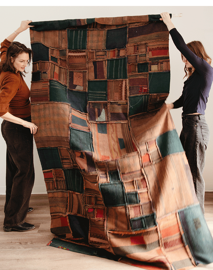 Amy and assistant holding up quilt