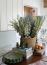 39 - Sissy Yellen, Seasonal table decor featuring a rustic woven basket filled with a blue and white floral arrangement, decorative green ceramic plates, stylish candlesticks, stacked coffee table books, and fresh citrus accents, creating a warm and inviting home design.