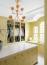 56 - Sissy Yellen, Luxurious custom closet featuring yellow cabinetry with mirrored doors, a marble countertop island, a striking gold lotus chandelier, and built-in wardrobe storage. The space is bathed in natural light from large arched windows, enhancing the elegant and organized design.